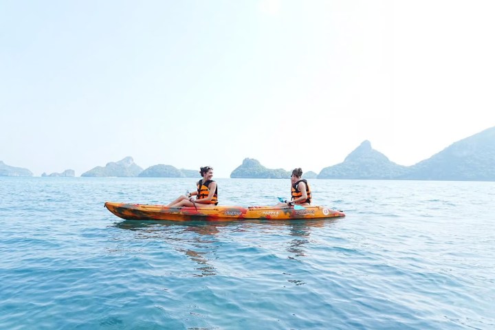 Two people kayaking on calm sea with distant islands.