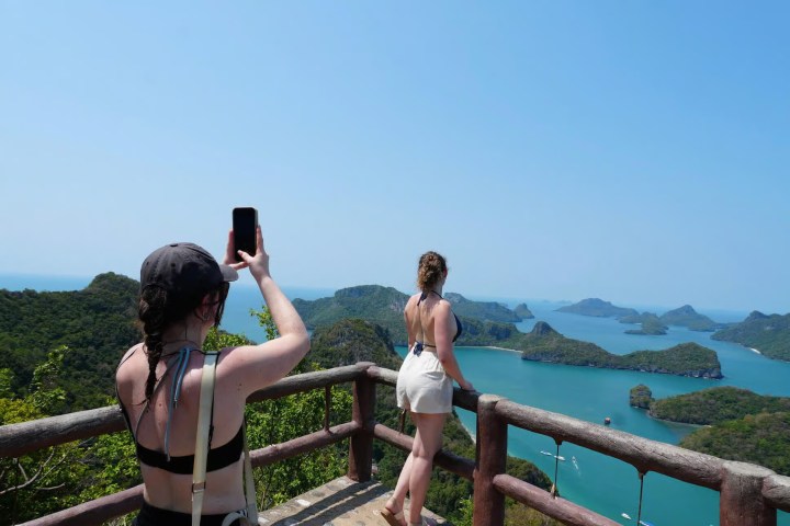 Two women on a lookout platform with a scenic view of islands and blue water.