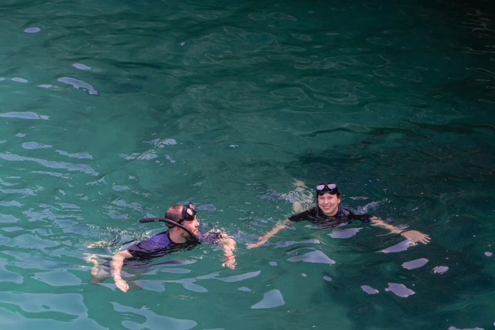 Two snorkelers swim in clear turquoise water.