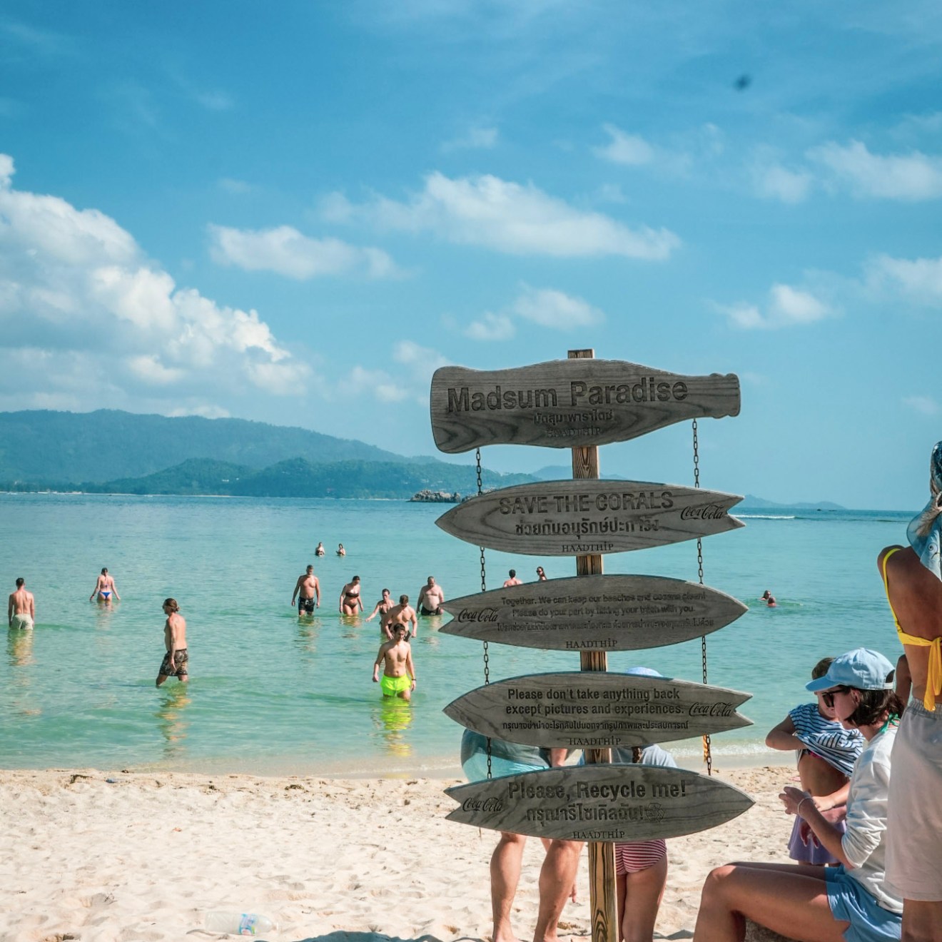 Beach scene with people and a wooden directional sign.