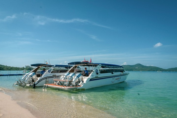 Two speedboats moored on a calm beach with clear skies.