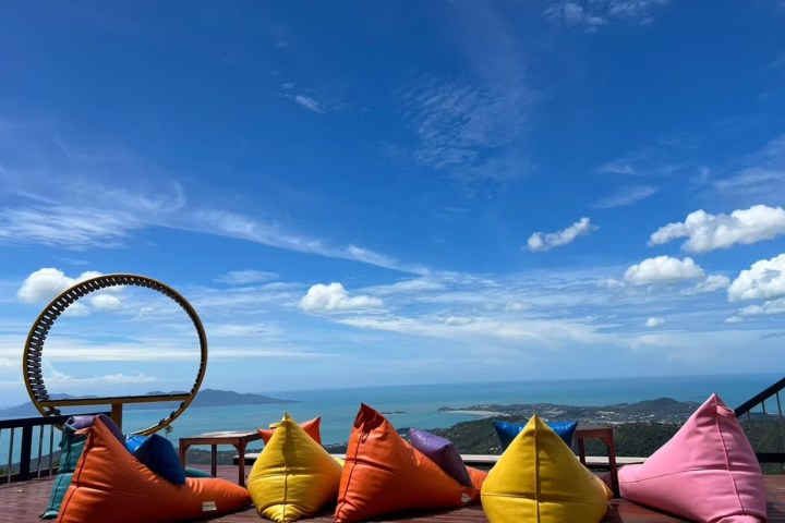 Colorful bean bags on a deck overlooking the ocean under a clear blue sky.