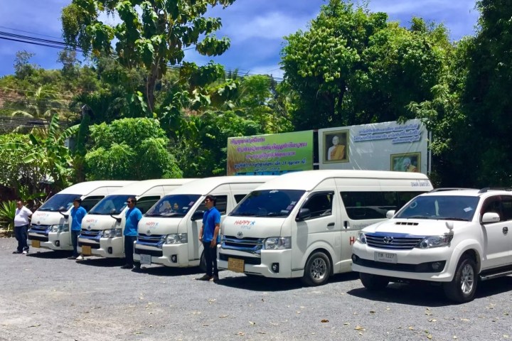 Six white vans and an SUV parked in a row on a sunny day.