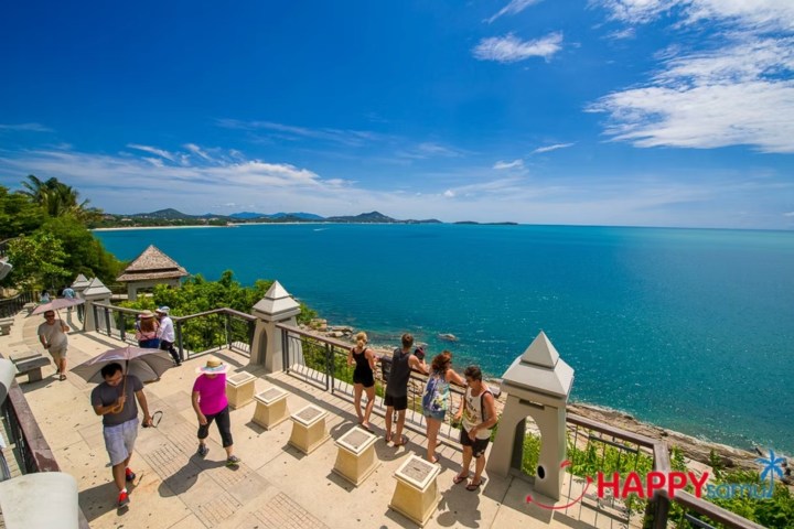 People enjoying ocean view from terrace with clear blue sky.