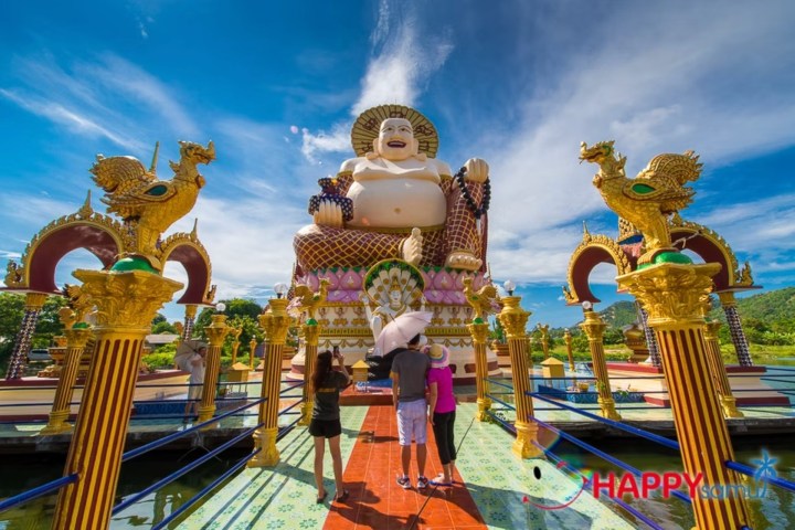 People at a temple with a large Buddha statue and dragon sculptures.