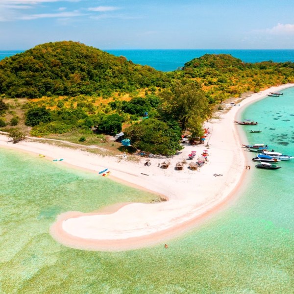 Aerial view of a sandy beach with turquoise water and lush green hills.