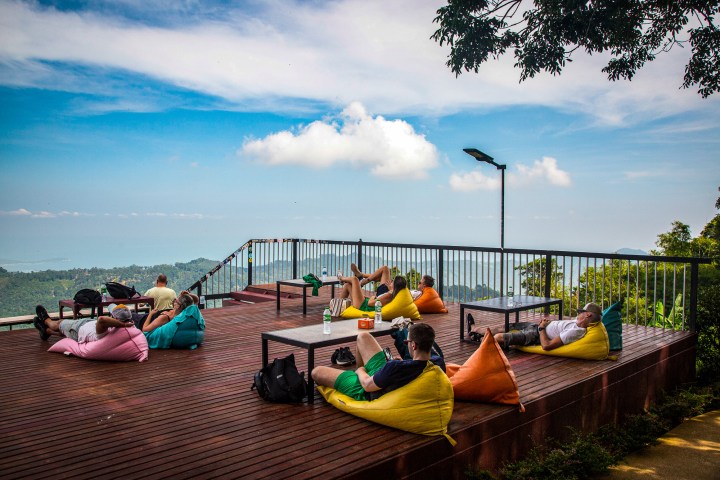 People relaxing on colorful bean bags on a wooden deck with a scenic mountain view.