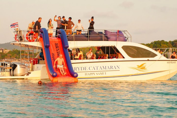People enjoying a boat with a waterslide on a sunny day.