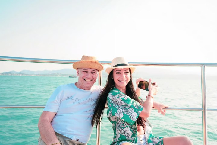 Smiling couple on a boat in sunny weather with a sea view.