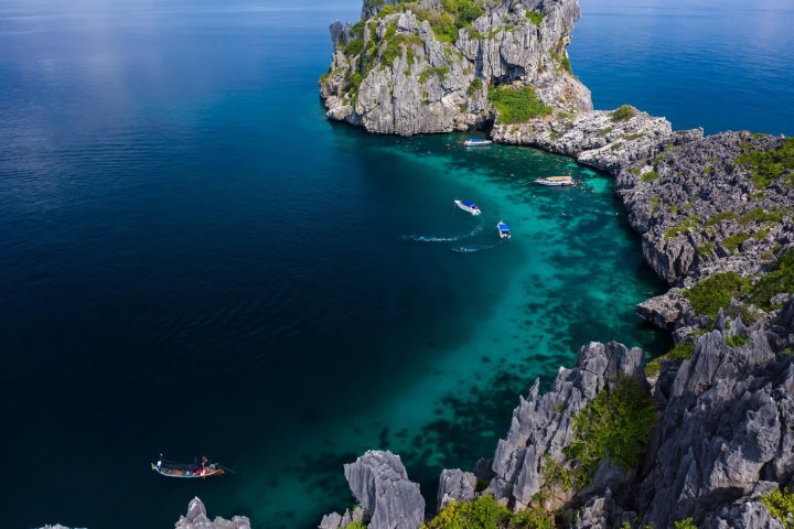 Aerial view of boats in a blue lagoon surrounded by rocky cliffs.
