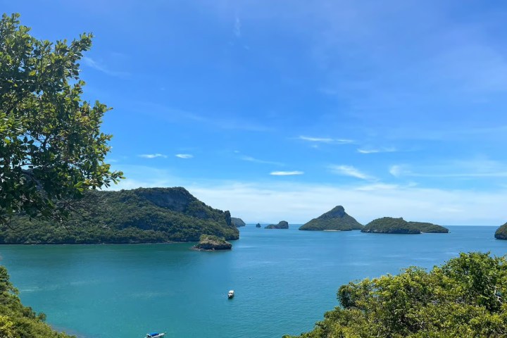 Tropical seascape with islands, blue sky, and boats on calm water.