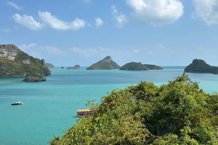 Scenic view of turquoise sea with islands and a wooden platform, under a blue sky with clouds.