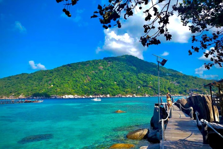 Scenic view of a pier over turquoise water with a mountain in the background.