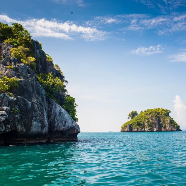 Ocean view with rocky islands covered in greenery under a blue sky.