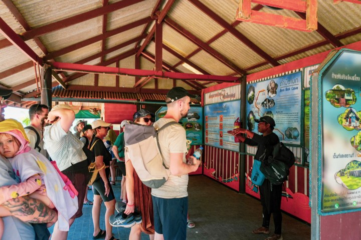 Tourists listening to a guide at an outdoor information center.