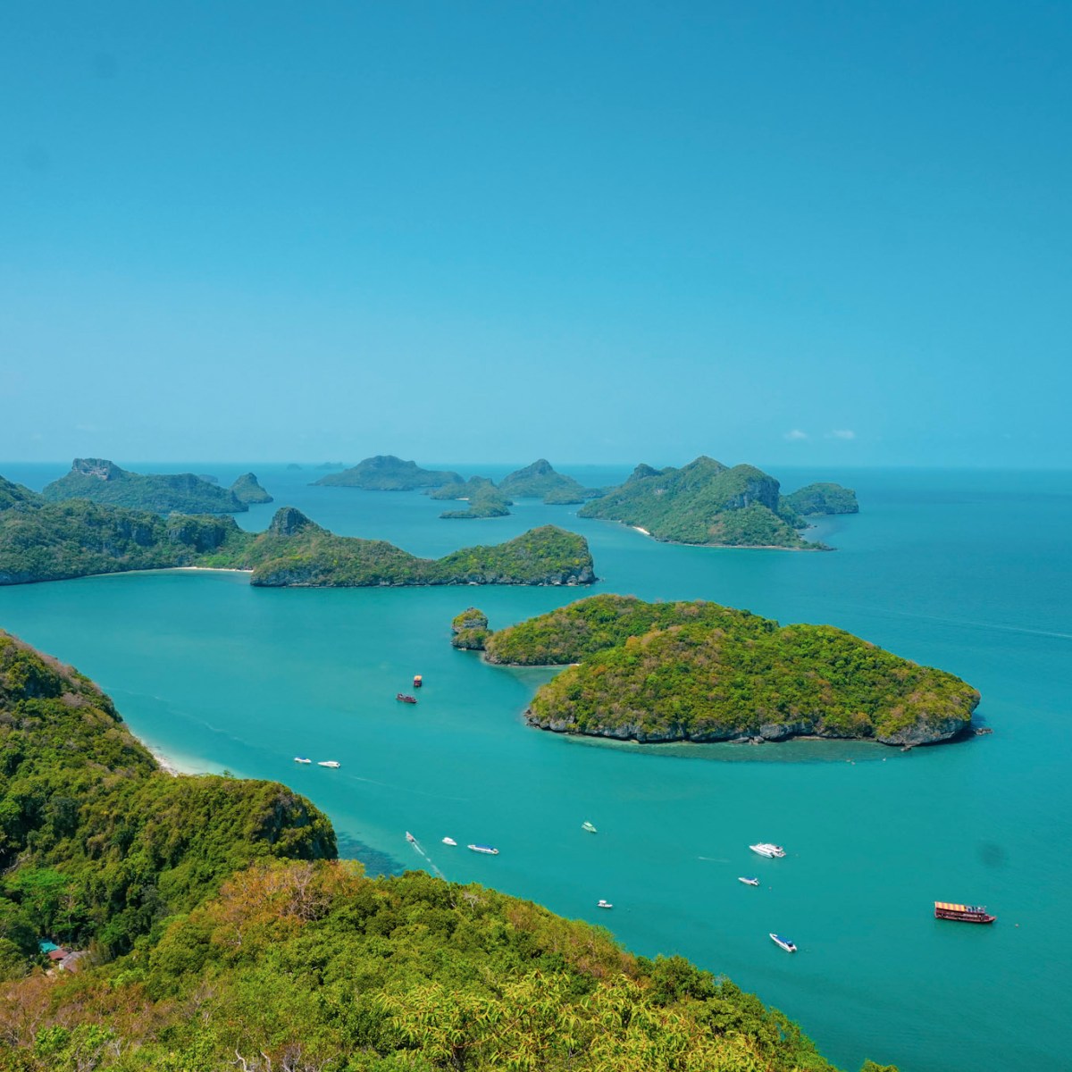 Aerial view of lush green islands in a clear blue sea under a bright sky.