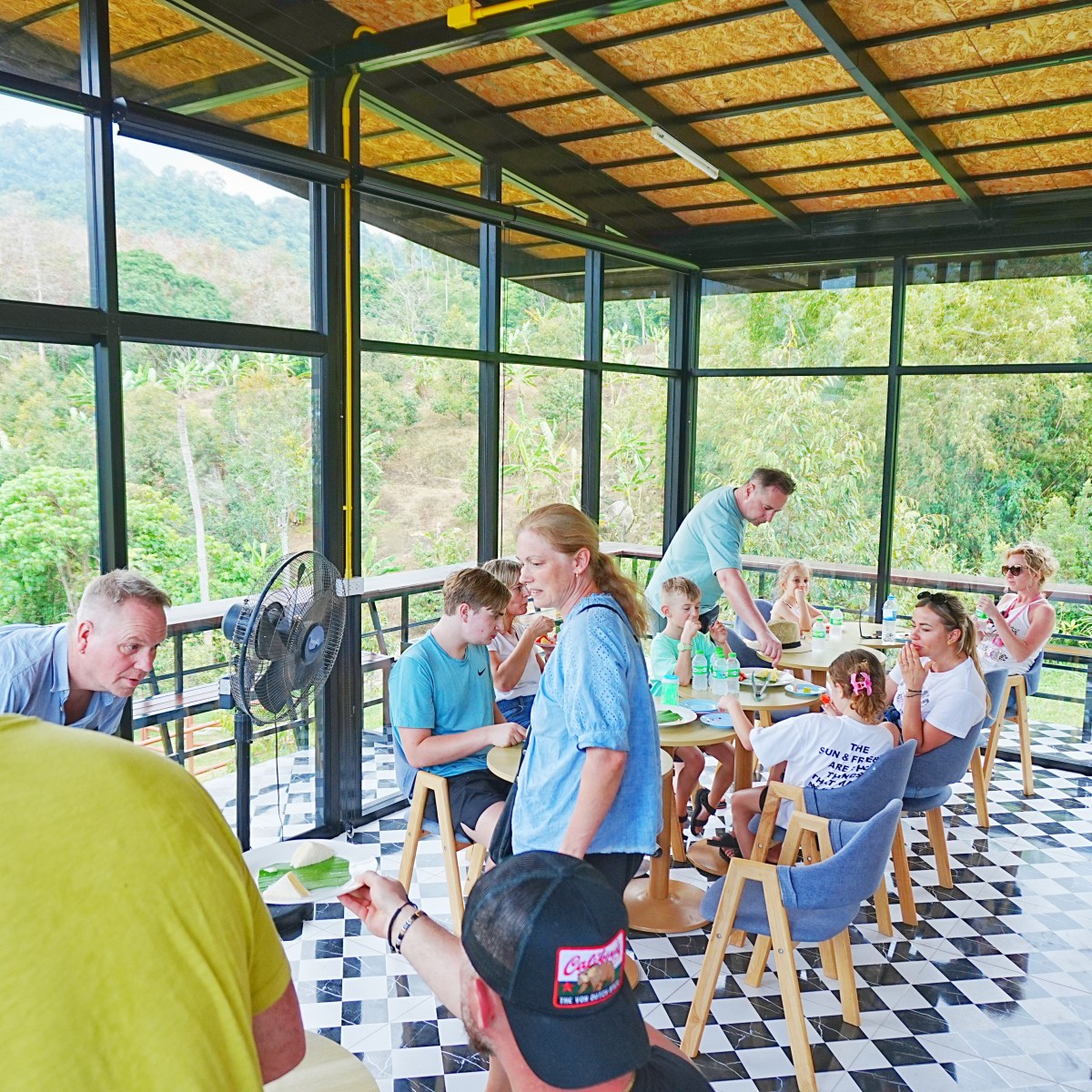 People enjoying a meal in a glass-walled restaurant with mountain views.