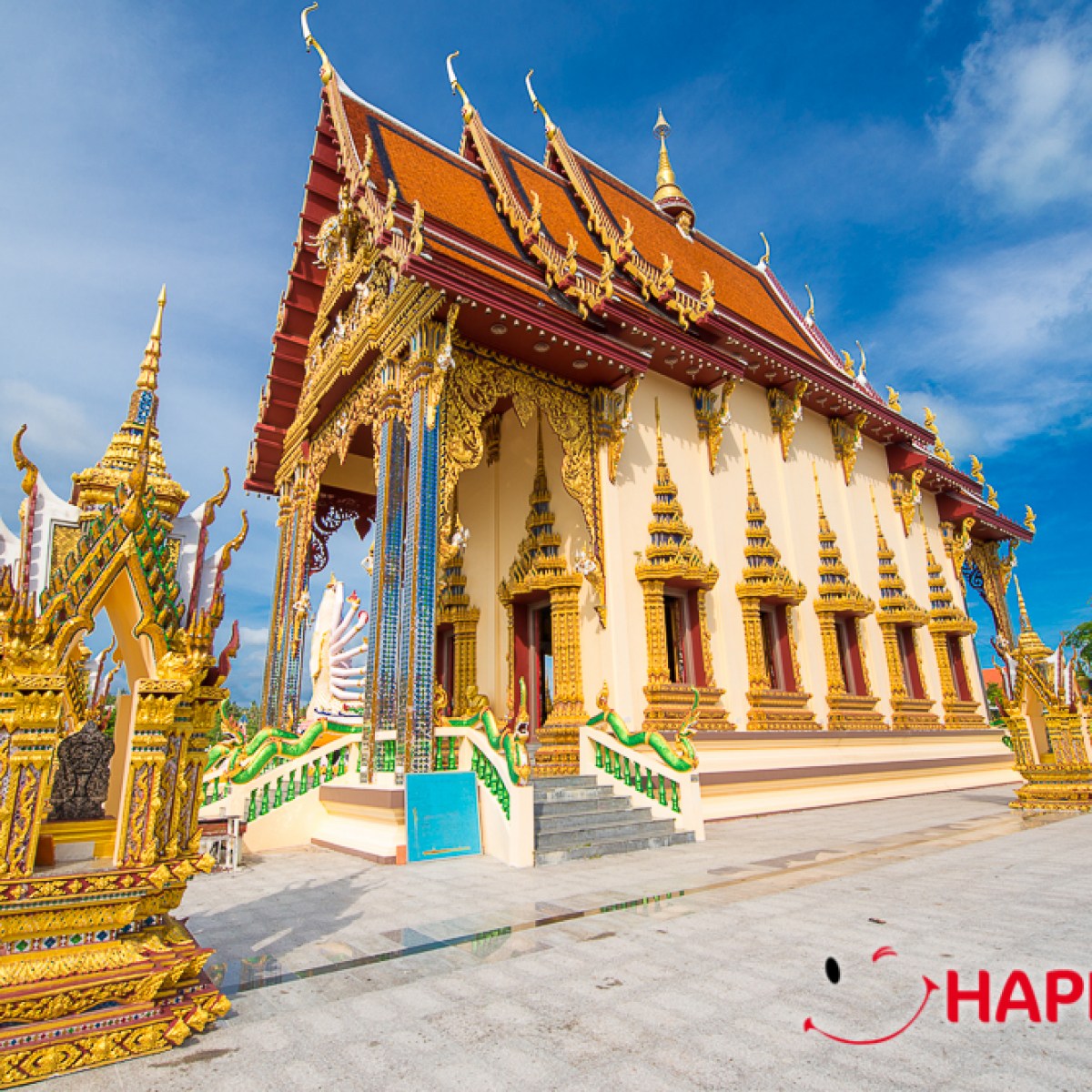 Ornate temple with gold detailing and red roof against a blue sky.