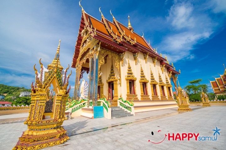 Ornate temple with gold detailing and red roof against a blue sky.